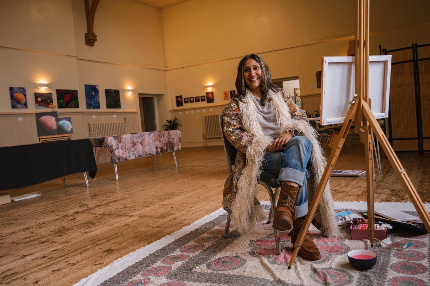 Simmi Sandhu seated at her easel at The Divine Feminine, Great Wood Community Hall